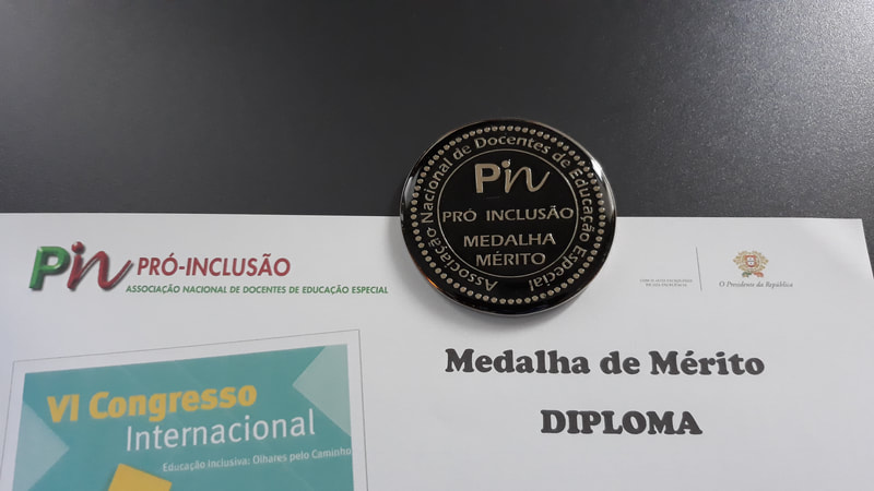 Medalha de Mérito parcialmente sobre o Diploma. Inscrição na Medalha: Pin, Pró-Inclusão, Medalha de Mérito